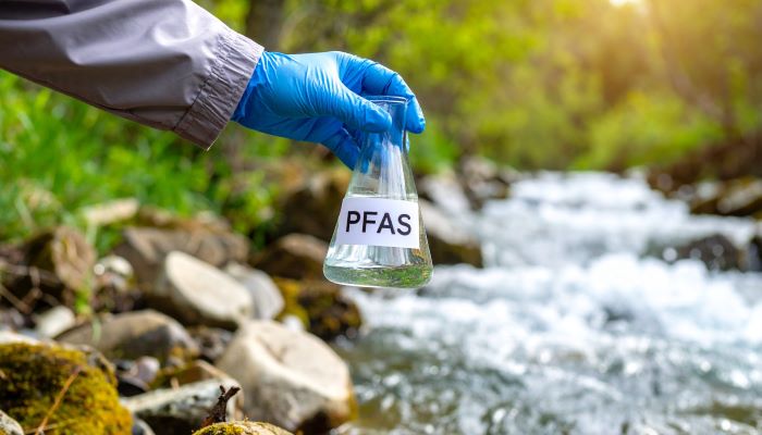 PFASと記載されたフラスコに河川水を汲む様子