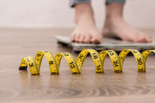 Tape measure in front of person standing on scale.